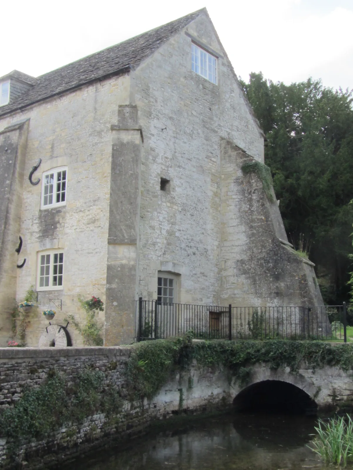 Kamienny budynek i mostek nad wodą w Bibury